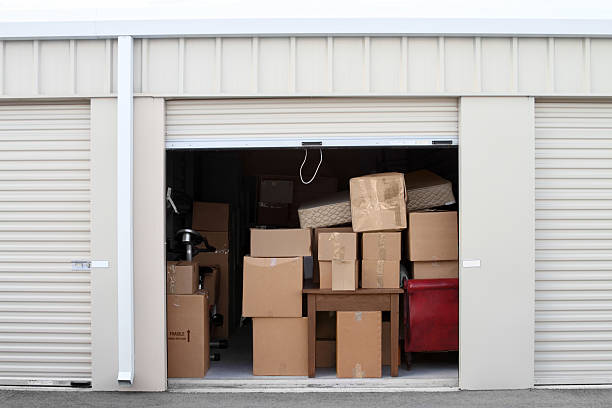 Warehouse building with self storage units. Self storage facility. Roll up doors on self storage facility. One door open with boxes and furniture in doorway.